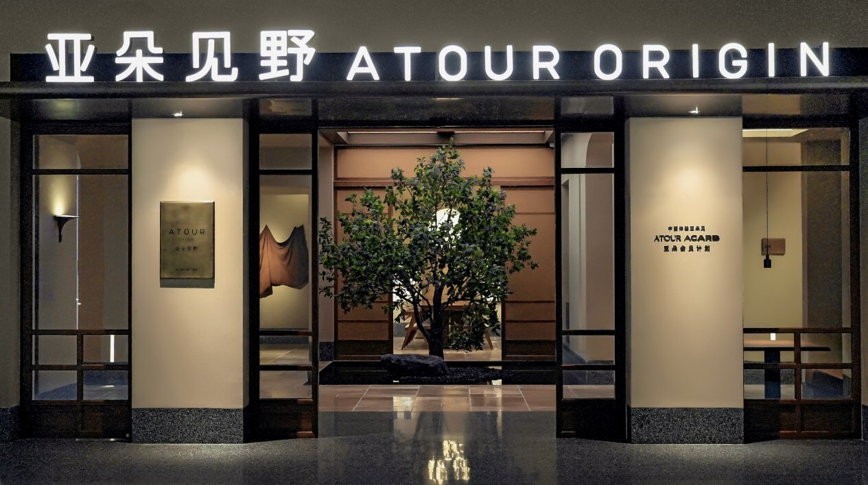 亚朵见野（ATOUR ORIGIN）门店入口夜景，门内有一棵树